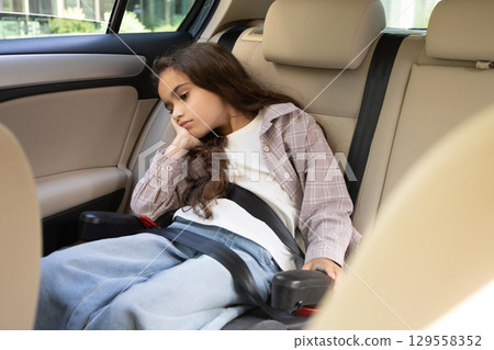 Cute girl waiting for her mom in the car and looking bored 129558352
