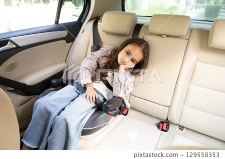 Cute girl waiting for her mom in the car and looking bored 129558353
