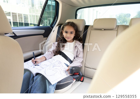 Cute girl sitting in a care and spending time on drawing 129558355