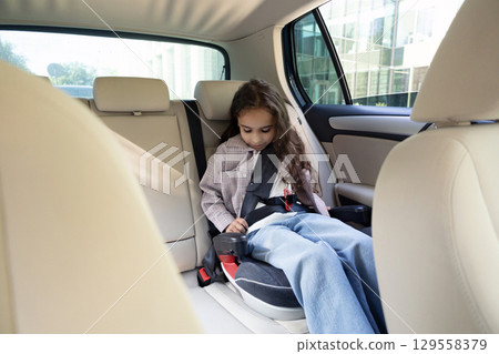 Dark-haired cute girl sitting in a car with her safety belt fixed 129558379