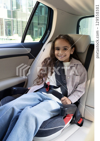 Dark-haired cute girl sitting in a car with her safety belt fixed Dark-haired cute girl sitting in a car with her safety belt fixed 129558381
