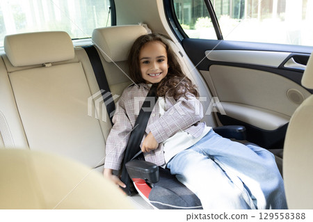 Dark-haired cute girl sitting in a car with her safety belt fixed 129558388