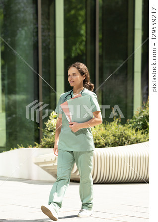 Female doctor in a green lab coat looking confident and contented Female doctor in a green lab coat looking confident and contented 129559217