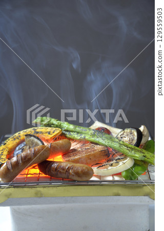 Grilling meat and vegetables on a smoky charcoal grill 129559503