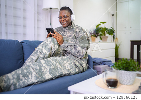 Relaxed Soldier Enjoying Music on a Couch 129560123