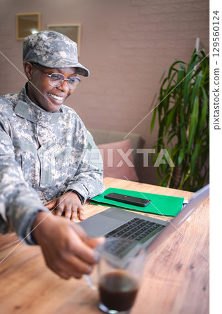 Smiling african american soldier working from home taking a coffee break Smiling african american soldier working from home taking a coffee break 129560124