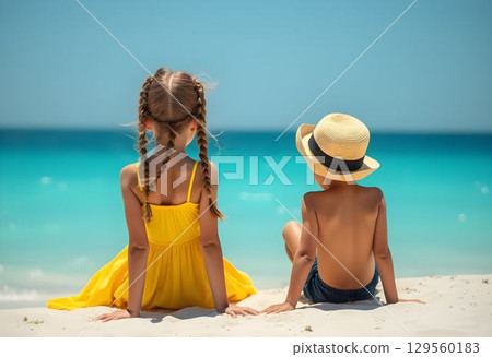 Children enjoy a sunny beach day while sitting on the soft sand overlooking the turquoise ocean water Children enjoy a sunny beach day while sitting on the soft sand overlooking the turquoise ocean water 129560183