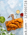 Chicken tenders served on a wooden board with salad and sauces 129560728