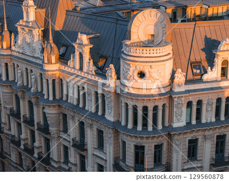 Art Nouveau building in Riga, Latvia, with sculpted figures, Alberta street, ornate columns, and dormer windows, illuminated by warm sunset light. 129560878