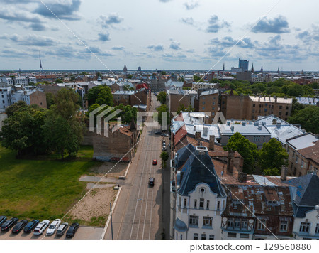 Scenic aerial view of Riga, Latvia, featuring Jugendstil buildings, the Riga TV Tower, green spaces, urban infrastructure, and a partly cloudy sky. 129560880