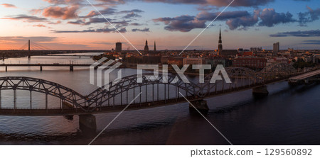 Riga, Latvia at sunset featuring the Daugava River, Railway Bridge, Riga TV Tower, Vansu Bridge, and spires of St. Peter's Church in the old town. Riga, Latvia at sunset featuring the Daugava River, Railway Bridge, Riga TV Tower, Vansu Bridge, and spires of St. Peter's Church in the old town. 129560892