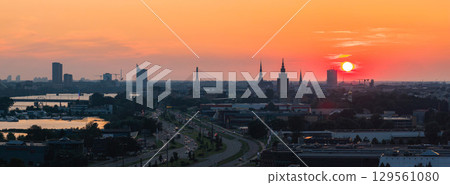 Sunset view of Riga, Latvia, featuring the Riga TV Tower, Vansu Bridge, old town spires, urban structures, and the Daugava River with surrounding greenery. Sunset view of Riga, Latvia, featuring the Riga TV Tower, Vansu Bridge, old town spires, urban structures, and the Daugava River with surrounding greenery. 129561080