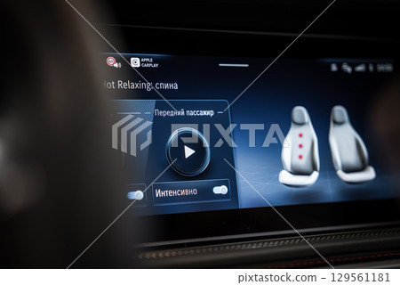 Infotainment screen in a high end vehicle shows massage seat controls in Russian, Apple CarPlay logo, and highlighted seat massage areas. 129561181