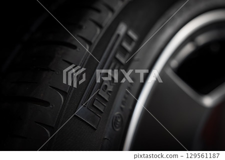 Close up view of a Pirelli tire showing embossed branding, detailed tread pattern, and sleek metallic wheel rim against a blurred background. Close up view of a Pirelli tire showing embossed branding, detailed tread pattern, and sleek metallic wheel rim against a blurred background. 129561187