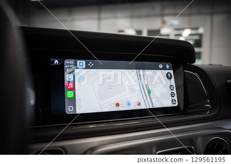 Infotainment screen shows a map with AUTOSALON PARK 7, app icons, and 4G connectivity. Black dashboard with red stitching in a modern indoor space. Infotainment screen shows a map with AUTOSALON PARK 7, app icons, and 4G connectivity. Black dashboard with red stitching in a modern indoor space. 129561195