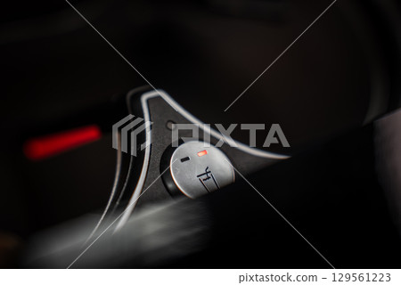A detailed view of a metallic car interior glass heating control knob with a red indicator light, surrounded by sleek black and silver design elements. A detailed view of a metallic car interior glass heating control knob with a red indicator light, surrounded by sleek black and silver design elements. 129561223