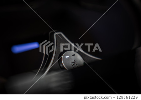 Detailed view of a metallic cup holder cooling knob with illuminated indicators, set against a dark interior with faint blue light in the background. 129561229