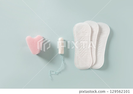 Female different tampons, daily pads on blue background. Hygiene accessories for women. View from above. 129562101