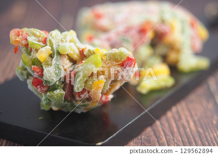 Colorful frozen vegetable mix on black serving platter 129562894