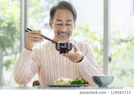 A man in his 60s eating 129563713
