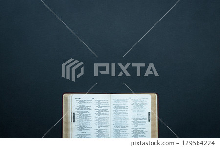 Open bible on top of dark surface. 129564224