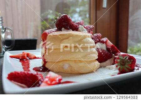 A morning of fluffy pancakes and strawberries — A moment at a cafe bathed in natural light A morning of fluffy pancakes and strawberries — A moment at a cafe bathed in natural light 129564383
