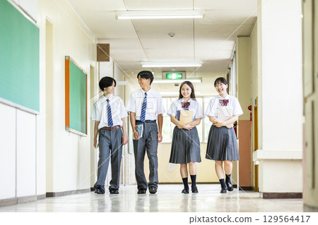 Male and female high school students walking down the school corridor 129564417