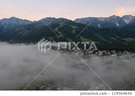 The townscape of Hakuba Village and the Hakuba Mountain Range seen through a sea of clouds in the early morning of summer. Hakuba Village, Nagano Prefecture (aerial shot by drone) The townscape of Hakuba Village and the Hakuba Mountain Range seen through a sea of clouds in the early morning of summer. Hakuba Village, Nagano Prefecture (aerial shot by drone) 129564649