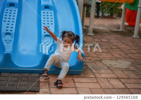 happy toddler baby girl sliding and playing at playground 129565108