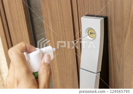 Image of spraying lubricant into the keyhole of a front door Image of spraying lubricant into the keyhole of a front door 129565795
