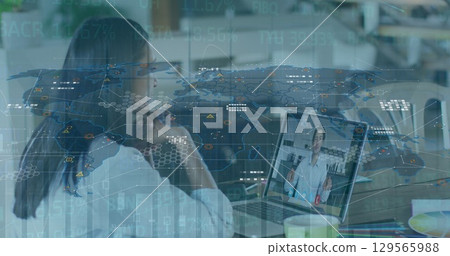 Image of graphs and world map over woman having image call on laptop 129565988
