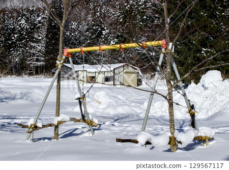 A scene of playground equipment buried in snow and unusable in a park A scene of playground equipment buried in snow and unusable in a park 129567117