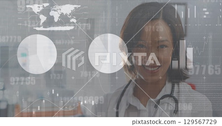Image of interface screen with charts and data over portrait of smiling asian female doctor 129567729