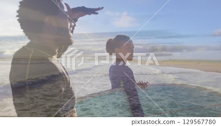 Image of sea over african american couple with surfboards at beach 129567780