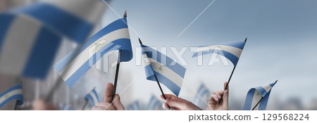Nicaragua flags in their hands on a blurred urban background Nicaragua flags in their hands on a blurred urban background 129568224