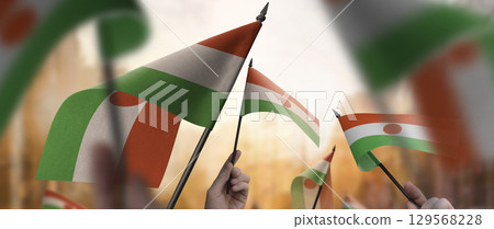 Niger flags in their hands on a blurred urban background 129568228
