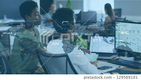 Image of world map and icons over diverse female coworkers working in office 129569181