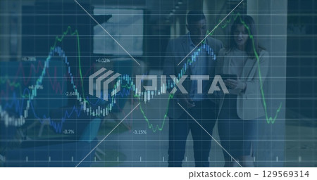Image of graph data moving over multiracial partners discussing with tablet in office lobby 129569314