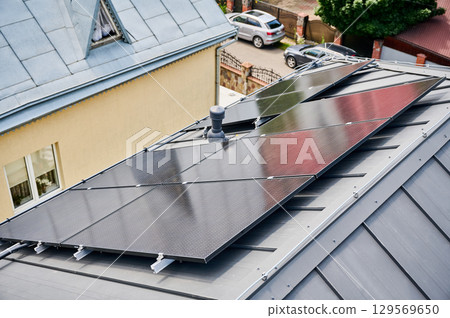 House with solar panels on rooftop for generating electricity through photovoltaic effect. Home with solar power system on roof. Concept of alternative energy, autonomy, power sustainable resources. House with solar panels on rooftop for generating electricity through photovoltaic effect. Home with solar power system on roof. Concept of alternative energy, autonomy, power sustainable resources. 129569650