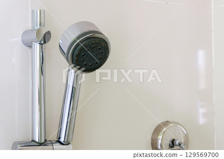 Showerhead with chrome finish mounted on a white wall. 129569700