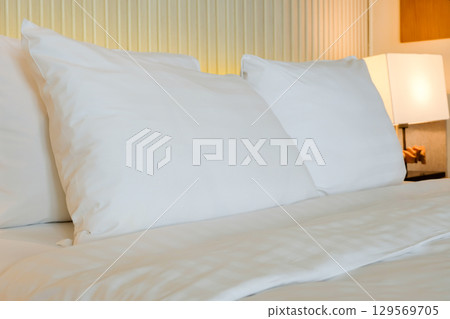 Clean white pillows on a neatly made bed with soft linens. 129569705