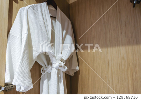 Cozy robe hanging in a wooden closet. 129569710