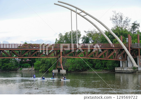 Bridge over water with a modern design and people kayaking beneath it. Mangrove Forest Learning Center Phra Chedi Klang Nam Rayong Thailand 129569722