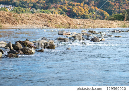 Scenic Hozugawa River with rocks and autumn foliage backdrop 129569920