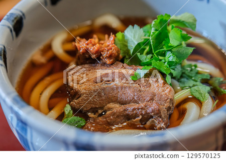 Delicious bowl of Udon Japanese noodle soup with herbs and meat 129570125