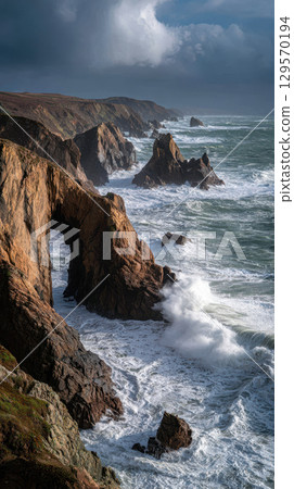 Dramatic rocky coastline with natural arch, crashing waves, and moody sky, remote and wild Dramatic rocky coastline with natural arch, crashing waves, and moody sky, remote and wild 129570194