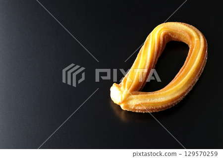 Churros photographed against a black background 129570259