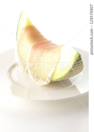 Raw ham and melon photographed on a white background 129570807