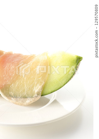 Raw ham and melon photographed on a white background 129570809