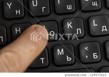 one black keyboard with Russian and English letters in white, bilingual computer keyboard layout with Latin and Cyrillic alphabet 129571023